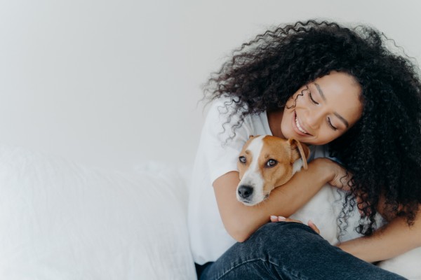 tutora sorrindo abraça seu cachorro recém adotado. O cachorro olha para a leitora com uma cara de felicidade. cachorra-para-adotar